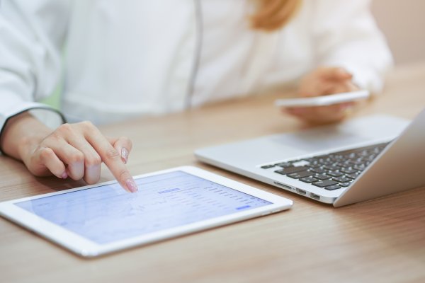 Sage Business Cloud Accounting Software features woman at desk in office on laptop and tablet with smartphone in hand